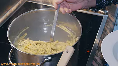Spätzle mit einer Kelle aus dem Wasser holen