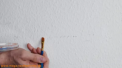 Fleck auf einer Wand wird mit einem Pinsel abgedeckt