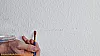 Fleck auf einer Wand wird mit einem Pinsel abgedeckt
